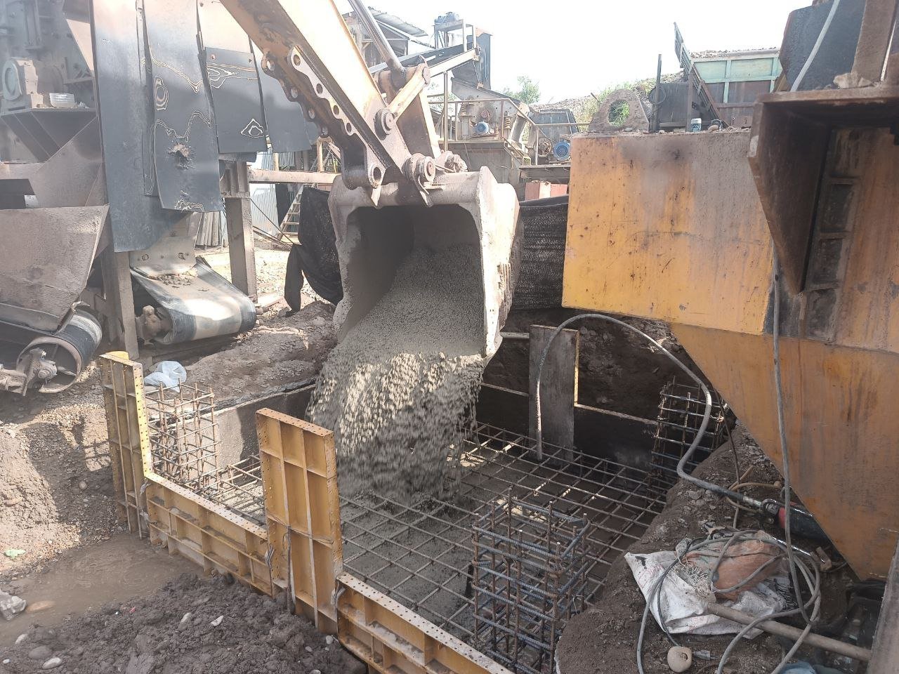 Concrete mixer truck pouring wet cement into a reinforced steel container at a construction site