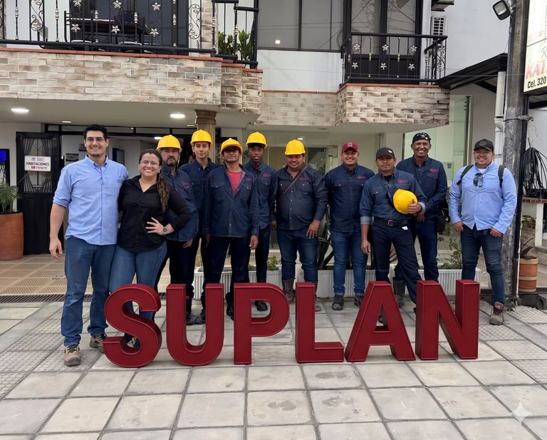 Group of construction workers and staff posing together in front of large red SUPLAN letters on a building entrance